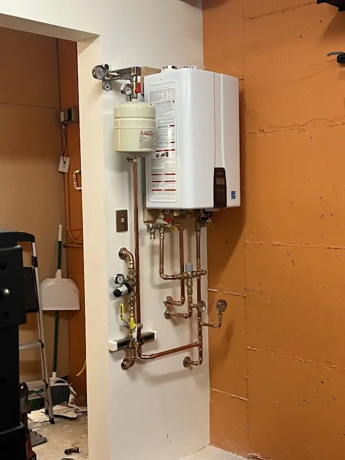 Plumbing technician inspecting water heater connections in Forest Hills